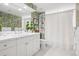 Bright bathroom featuring double vanity, decorative wallpaper, and walk-in shower with hexagon tile floor at 6375 E Tufts Ave, Englewood, CO 80111