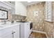 Functional laundry room with patterned wallpaper, sink, cabinets, and modern washer and dryer at 6375 E Tufts Ave, Englewood, CO 80111