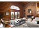 Open living room with log walls, brick fireplace, and access to a private balcony with scenic views at 29095 Summit Ranch Dr, Golden, CO 80401