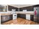 Well-equipped kitchen with dark cabinets, stainless steel refrigerator, gas range, and hardwood floors at 1940 E 95Th Ave, Thornton, CO 80229