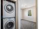 Convenient laundry room featuring stacked washer and dryer, adjacent to a cozy carpeted bedroom with natural light at 1940 E 95Th Ave, Thornton, CO 80229