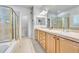 Bathroom featuring double sinks, walk-in shower, and natural wood cabinetry at 7193 S Versailles Way, Aurora, CO 80016