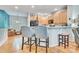 Eat-in kitchen features wood floors, light wood cabinetry, breakfast bar, and views of living area at 7193 S Versailles Way, Aurora, CO 80016