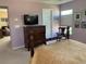 A bedroom with a traditional-style bed frame, wooden dresser, and a mounted television on a calming lavender-colored wall at 10634 Ashfield St, Highlands Ranch, CO 80126
