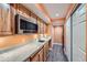 Galley kitchen featuring stainless steel microwave, light wood cabinetry, and a marble countertop at 1824 Morningview Ln, Castle Rock, CO 80109