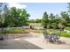 Backyard featuring a deck, stone patio, green lawn, mature trees, and a white picket fence at 7603 W Coal Mine Pl, Littleton, CO 80128