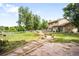 Expansive backyard featuring stone pavers, a manicured lawn, lush trees, and the home's exterior at 7603 W Coal Mine Pl, Littleton, CO 80128