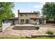 Backyard featuring a large deck, stone patio, green trees, and a white picket fence at 7603 W Coal Mine Pl, Littleton, CO 80128