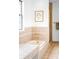 Bright bathroom features a tub with tiled surround, gold fixtures, and a modern art print at 7603 W Coal Mine Pl, Littleton, CO 80128