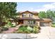 Charming two-story home with brick and siding exterior, lush landscaping, and attached two-car garage on a sunny day at 7603 W Coal Mine Pl, Littleton, CO 80128