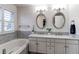 Bathroom with double vanity sinks, large soaking tub, and shuttered window at 4889 S Elkhart Ct, Aurora, CO 80015