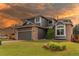 Charming two-story home with manicured front lawn, gray siding, and brick accents at sunset at 4889 S Elkhart Ct, Aurora, CO 80015