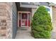 Close-up of the front door showcasing a red door, storm door and landscaped walkway at 4889 S Elkhart Ct, Aurora, CO 80015
