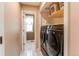 Laundry room with black washer and dryer and storage shelves at 4889 S Elkhart Ct, Aurora, CO 80015