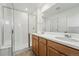 Bright bathroom featuring double sinks, sleek countertops, wood cabinetry, and a glass-enclosed shower at 2116 Chambers Rd, Brighton, CO 80601