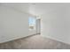 Bright bedroom features neutral carpet, a window offering outside views, and a white door at 2116 Chambers Rd, Brighton, CO 80601