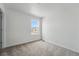 This bedroom features neutral carpet, a window with views of the neighborhood, and an electrical outlet at 2116 Chambers Rd, Brighton, CO 80601