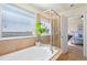Bright bathroom with a soaking tub, glass shower, and view into the main bedroom at 10554 Casper Pt, Parker, CO 80134