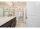 Bright bathroom featuring dark vanity with white countertop, modern mirror, and shower with tiled walls at 6776 Navajo Way, Denver, CO 80221