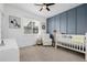 Modern bedroom featuring custom blue accent wall, white crib, plush seating, and stylish decor at 6776 Navajo Way, Denver, CO 80221