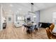 Open-concept living room featuring a fireplace, hardwood floors, and a dining area with modern light fixture at 6776 Navajo Way, Denver, CO 80221