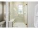 Modern tiled shower with a built-in bench, glass door, window, and chrome fixtures at 6776 Navajo Way, Denver, CO 80221