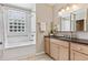 Bathroom with large tub, glass block window, and updated vanity with neutral cabinet color at 901 S Leyden St, Denver, CO 80224