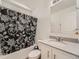 This bright bathroom features a shower with black and white curtain, and a sink with white cabinetry at 4987 N Walden Way, Denver, CO 80249