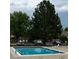 Community pool surrounded by mature trees with lounge chairs and clear blue water at 10251 W 44Th Ave # 3-204, Wheat Ridge, CO 80033
