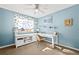 Blue home office with white desk, ceiling fan, large window, and stylish decor at 5211 E 116Th Ave, Thornton, CO 80233