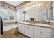 Bathroom with double sinks, decorative backsplash, soaking tub, and neutral tile flooring at 1844 S Jay Way, Lakewood, CO 80232
