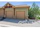 Two-car garage featuring stone accents, green siding, and a small green space to the side at 8778 S Kipling Way # 304, Littleton, CO 80127