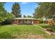 View of the home's brick facade, and covered porch from grassy backyard at 8304 Eaton Way, Arvada, CO 80003
