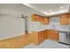 An open kitchen has white countertops, stainless appliances, and wood cabinets open to an adjacent room at 8304 Eaton Way, Arvada, CO 80003