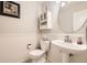 Charming half bathroom features pedestal sink, toilet, white wainscoting and decorative framed artwork at 9241 Roadrunner St, Highlands Ranch, CO 80129