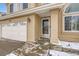 Close up of the front entrance of a tan home with a white garage door and covered porch at 9241 Roadrunner St, Highlands Ranch, CO 80129