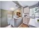 Compact kitchen with white cabinets, refinished hardwood floors, bar seating, and bright countertops at 2731 S Logan St, Englewood, CO 80113