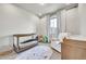 Bright Bedroom with a crib, white rocking chair, and a playful rug with car designs at 1575 W 68Th Ave, Denver, CO 80221