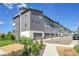 Modern townhouse complex with landscaped yard and attached garages under a bright blue sky at 1575 W 68Th Ave, Denver, CO 80221