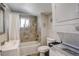 Bright bathroom featuring tiled walls, shower-tub combo, and convenient in-unit washer and dryer at 1866 S Pennsylvania St, Denver, CO 80210