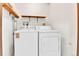 Close-up of a white washer and dryer set with open shelving above them for storage at 13134 Deneb Dr, Lone Tree, CO 80124