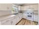 Bright kitchen featuring white cabinets, stainless steel sink, and hardwood floors at 1758 S Ensenada St, Aurora, CO 80017