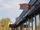 Shot of SloHi Coffee Co. featuring shop signs for various businesses against a blue sky backdrop at 2809 Yates St, Denver, CO 80212
