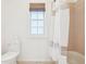 Bathroom showcasing a toilet, shower-tub combo with peach tiling, and a window with a woven shade at 742 Norwich Ct, Castle Pines, CO 80108