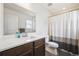 Bright bathroom with white countertops, wood cabinets and shower with modern striped curtain at 608 N Bersshine Ct, Watkins, CO 80137