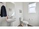 Clean, minimalist powder room with a pedestal sink, modern toilet, and a bright, airy feel at 608 N Bersshine Ct, Watkins, CO 80137