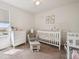 Bright and cozy Bedroom featuring a white crib, dresser, chair and ample natural light from the window at 608 N Bersshine Ct, Watkins, CO 80137