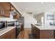 Open kitchen with stainless steel appliances, white countertops, and wood cabinets, creating a modern cooking space at 608 N Bersshine Ct, Watkins, CO 80137