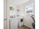 Well-lit laundry room equipped with modern washer and dryer units and ample shelving for storage at 608 N Bersshine Ct, Watkins, CO 80137