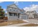 Two-story house with gray siding, a large front porch, and a two-car garage at 12243 Joplin St, Commerce City, CO 80603